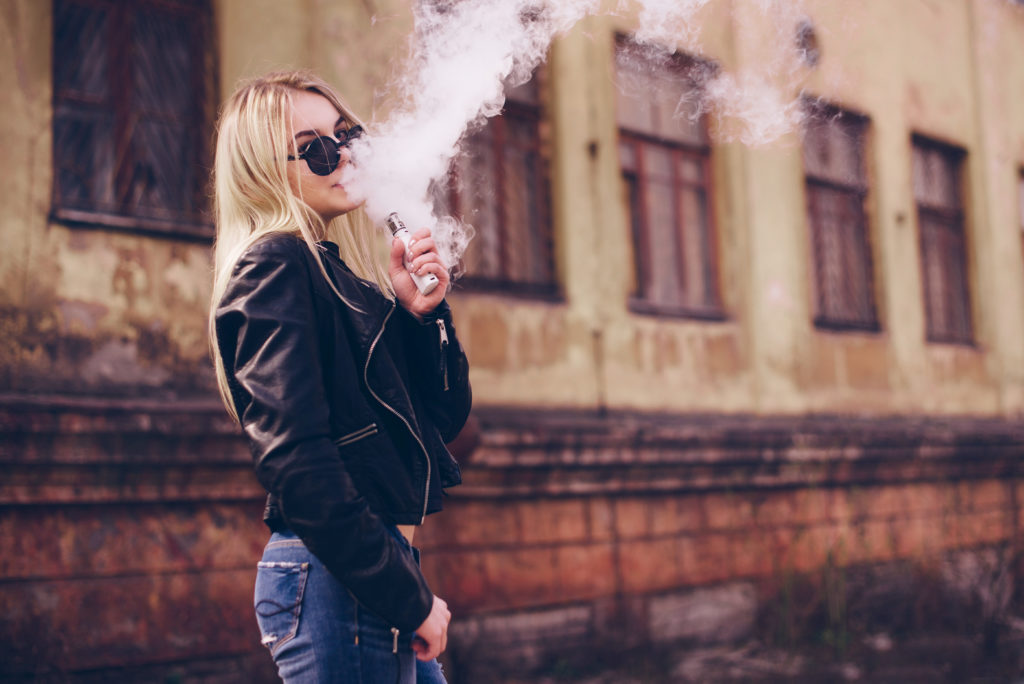 Woman vaping outside near an old building